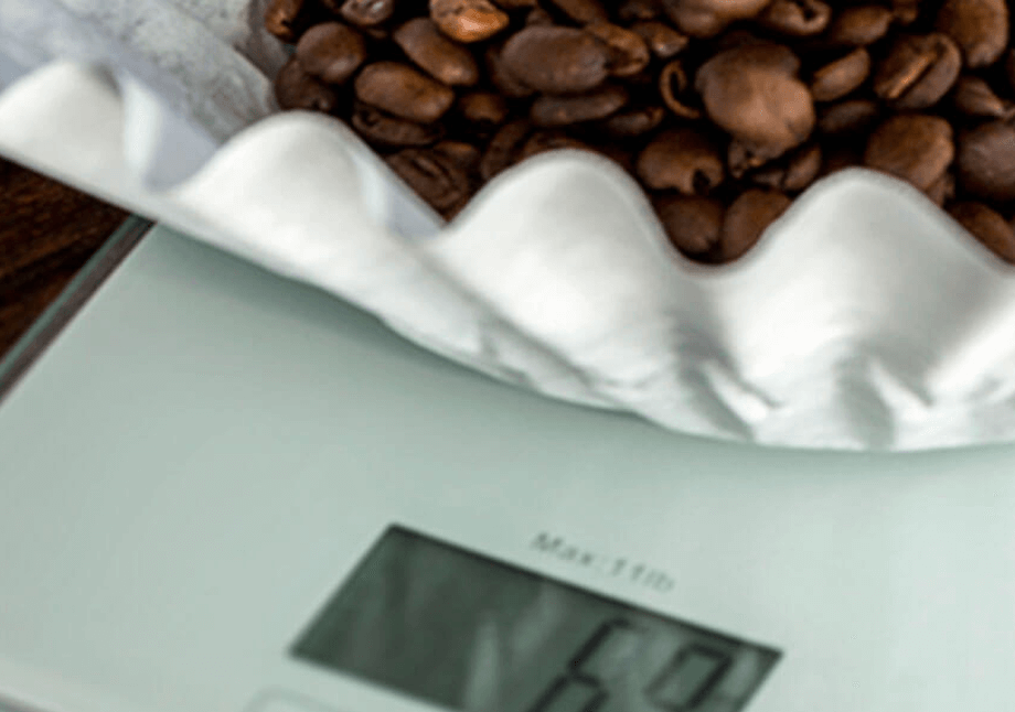Roasted coffee beans being weighed on a scale.