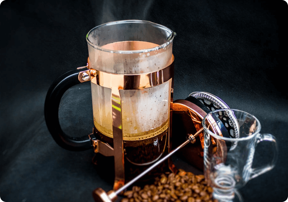 A French Press coffee maker containing hot brewed coffee.